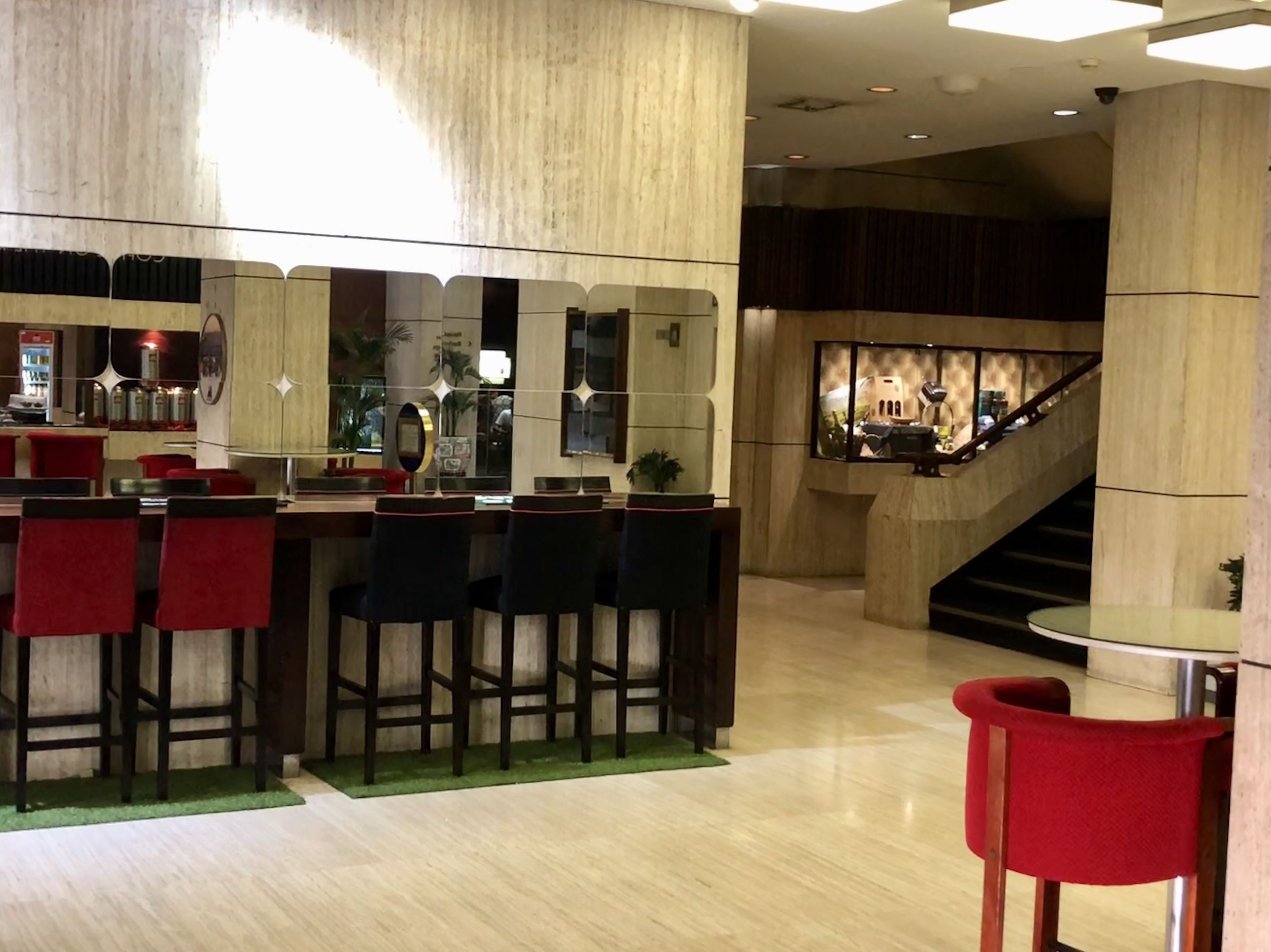 Un área de bar moderna con mostrador, taburetes y una escalera al fondo.