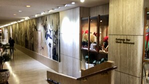 Un pasillo con un mostrador de recepción de madera, un mural en la pared y un cartel que anuncia 'Exchange Bar Ulundi Restaurant'.