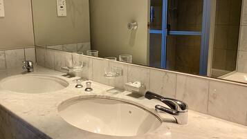 A bathroom with two sinks, a mirror, and a glass shower enclosure.