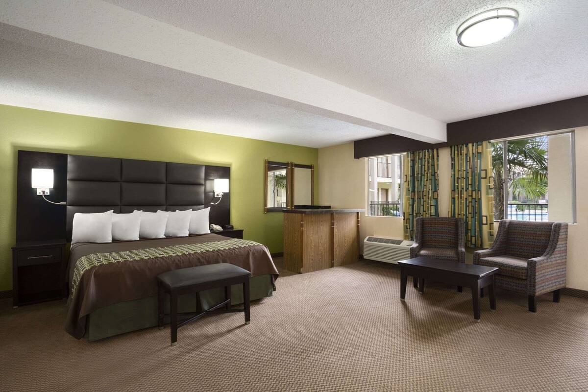 Ein Hotelzimmer mit Bett, Schreibtisch, Stuhl und einem Fenster mit Vorhängen.