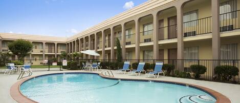 Un hôtel doté d’une piscine, de chaises longues et d’un patio couvert.