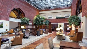 A spacious lobby with a high ceiling, brick walls, and multiple seating areas.