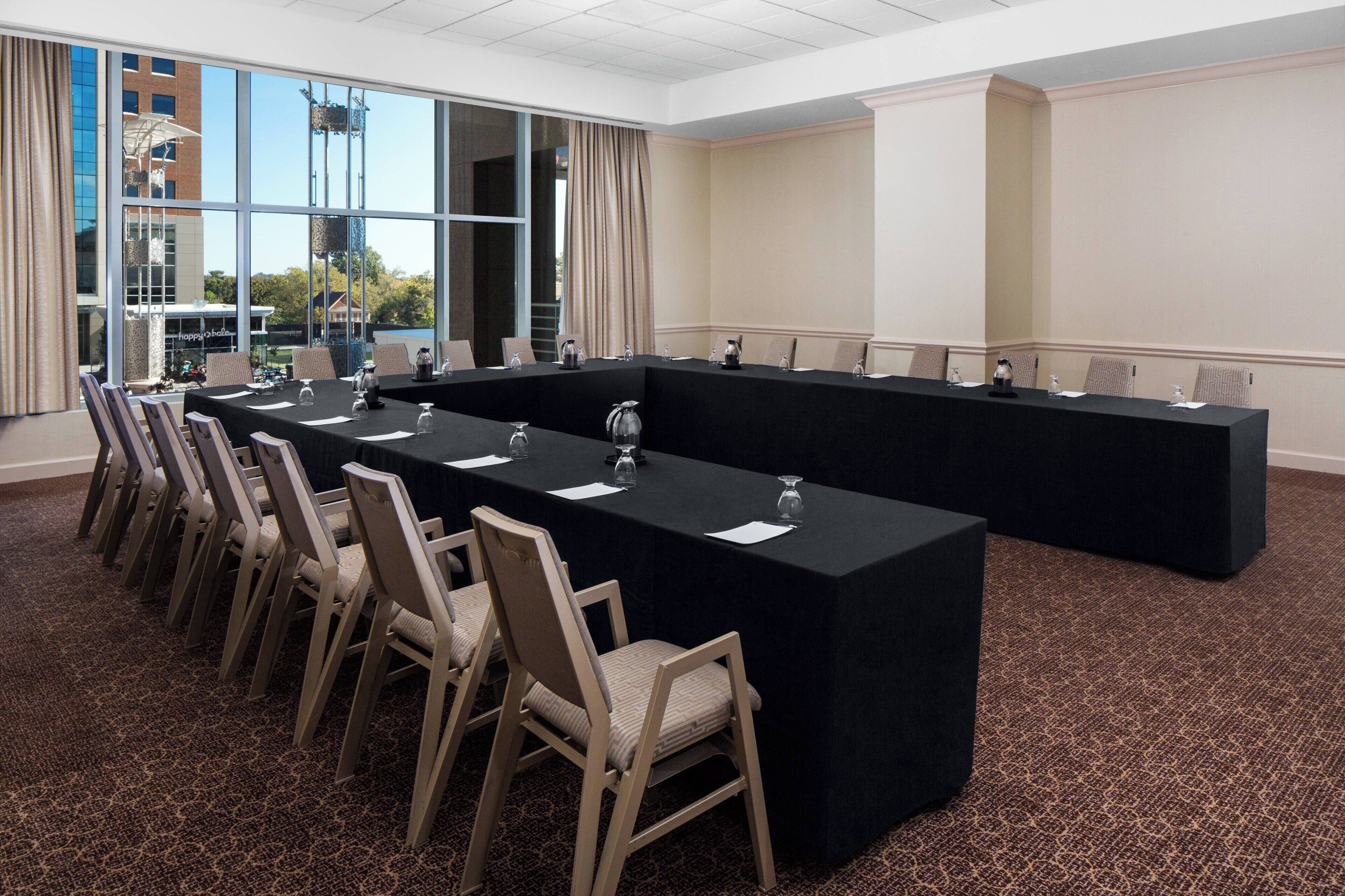A conference room with a long table, chairs, and a carpeted floor.