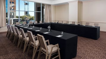 Una sala conferenze con un lungo tavolo, sedie e pavimento con tappeto.