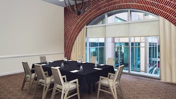 Una sala conferenze con un tavolo nero, sedie beige e un'ampia finestra ad arco che si affaccia all'esterno.