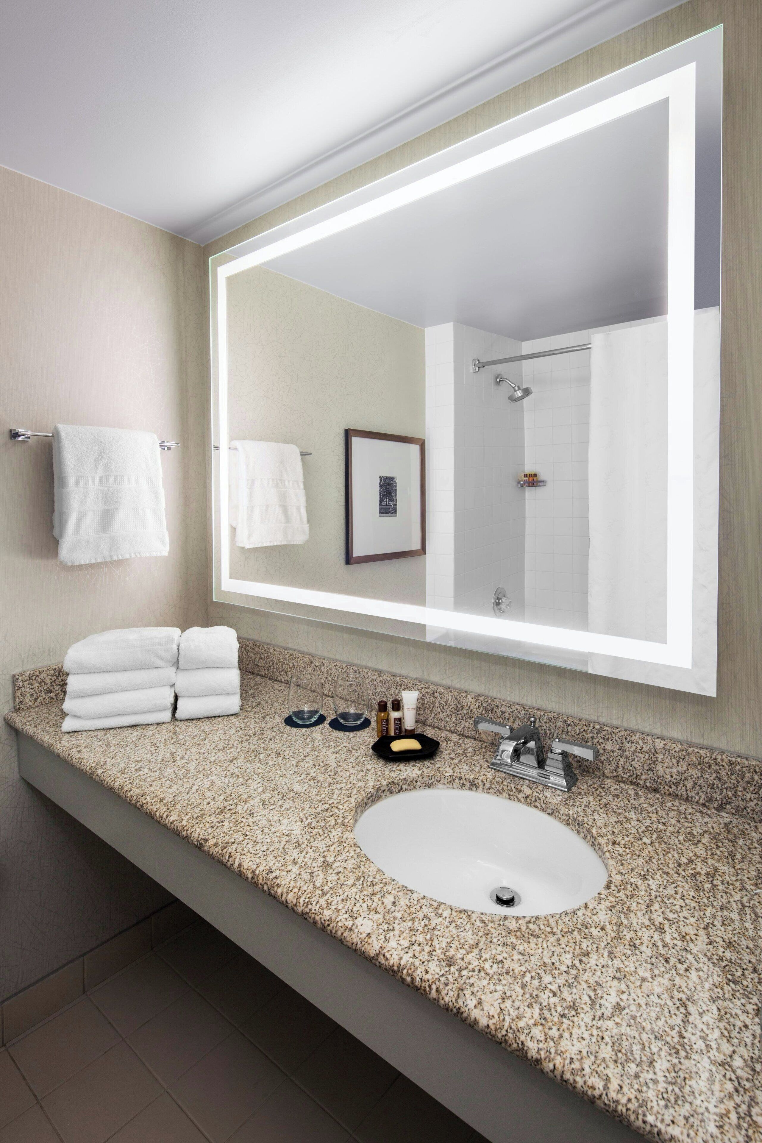 Un bagno con uno specchio grande, un lavandino e un porta asciugamani.