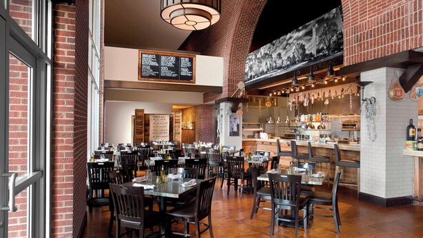 A restaurant with brick walls, wooden tables, and hanging lights.