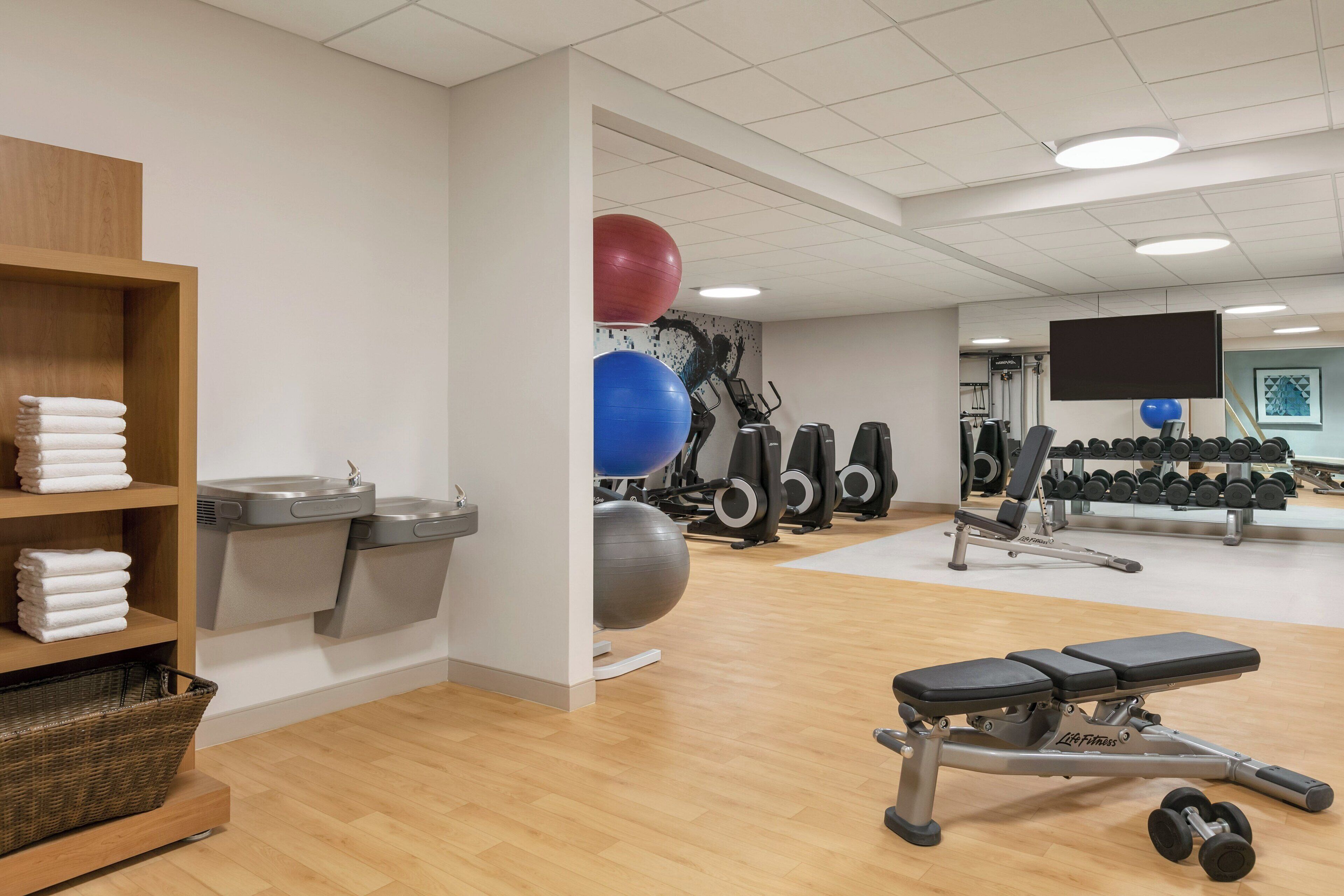 A gym with exercise equipment, a bench, and a wall-mounted TV.