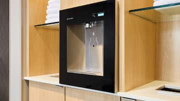 Ein moderner Wasserspender mit digitaler Anzeige, integriert in einen Holzkorpus mit weißer Arbeitsplatte.