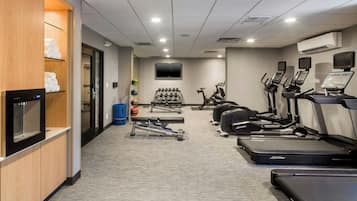 A gym with treadmills, elliptical machines, and weight benches.