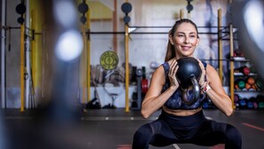 A person performing a squat exercise with a kettlebell in a gym setting.