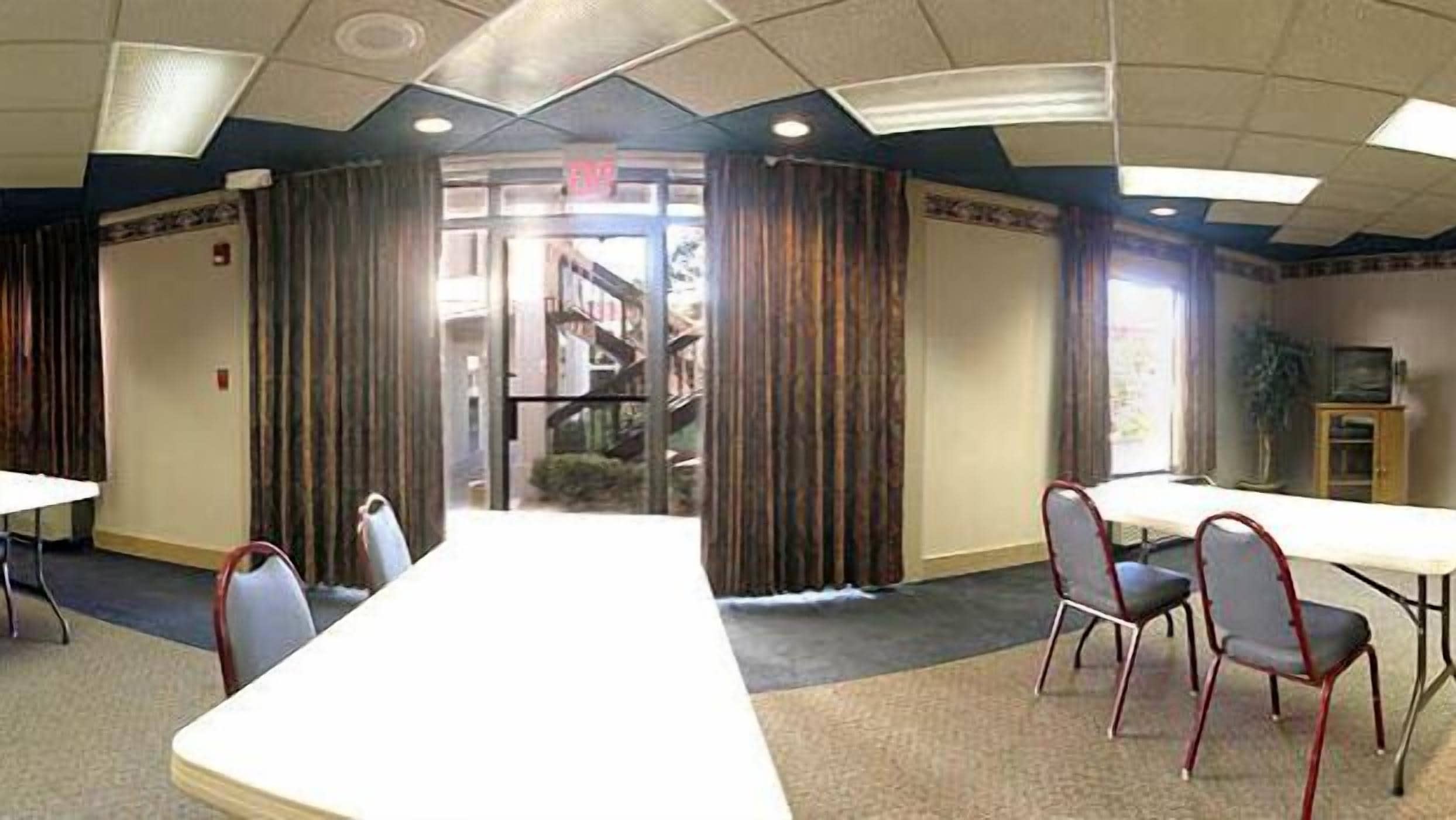 A conference room with a long table, chairs, and a view of a building through a glass door.