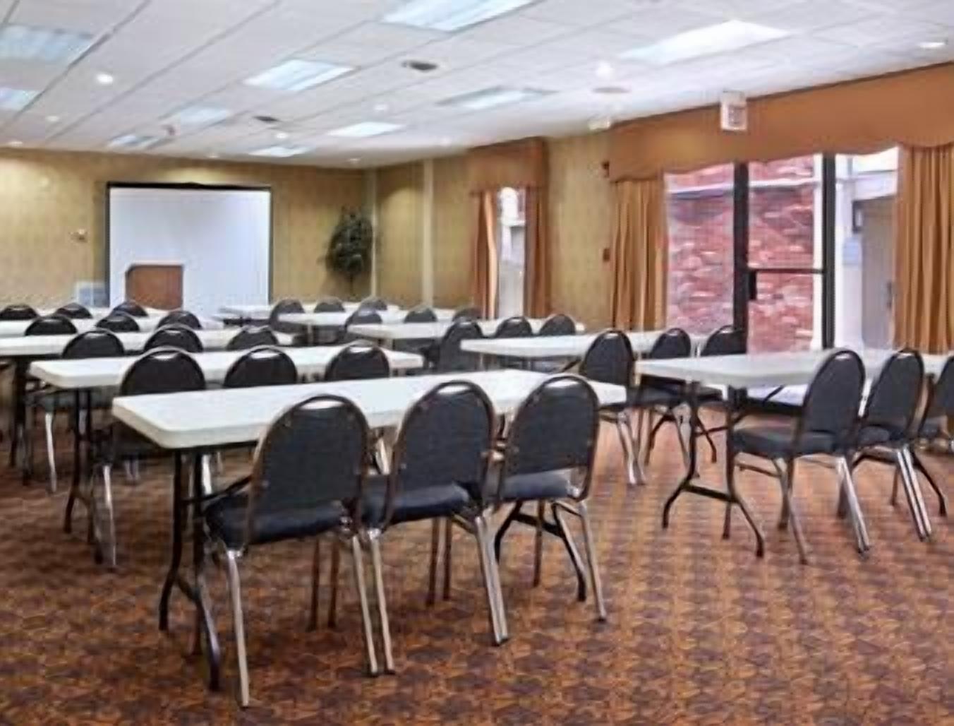 Un salón de conferencias con varias mesas y sillas, una pizarra y vistas al exterior a través de amplios ventanales.