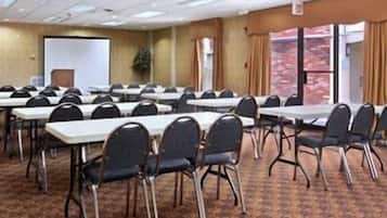 Un salón de conferencias con varias mesas y sillas, una pizarra y vistas al exterior a través de amplios ventanales.
