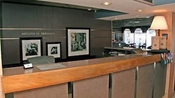 A reception desk with a "welcome to Lebanon" sign, framed pictures on the wall, and a lamp on the right.