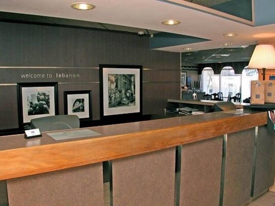 A reception desk with a "welcome to Lebanon" sign, framed pictures on the wall, and a lamp on the right.