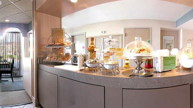 Un mostrador de buffet con diversos alimentos expuestos en recipientes transparentes y bajo campanas de cristal.