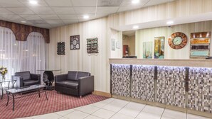 Un área de recepción con piso de baldosas, dos sofás, una mesa de vidrio y un tapete rojo estampado.