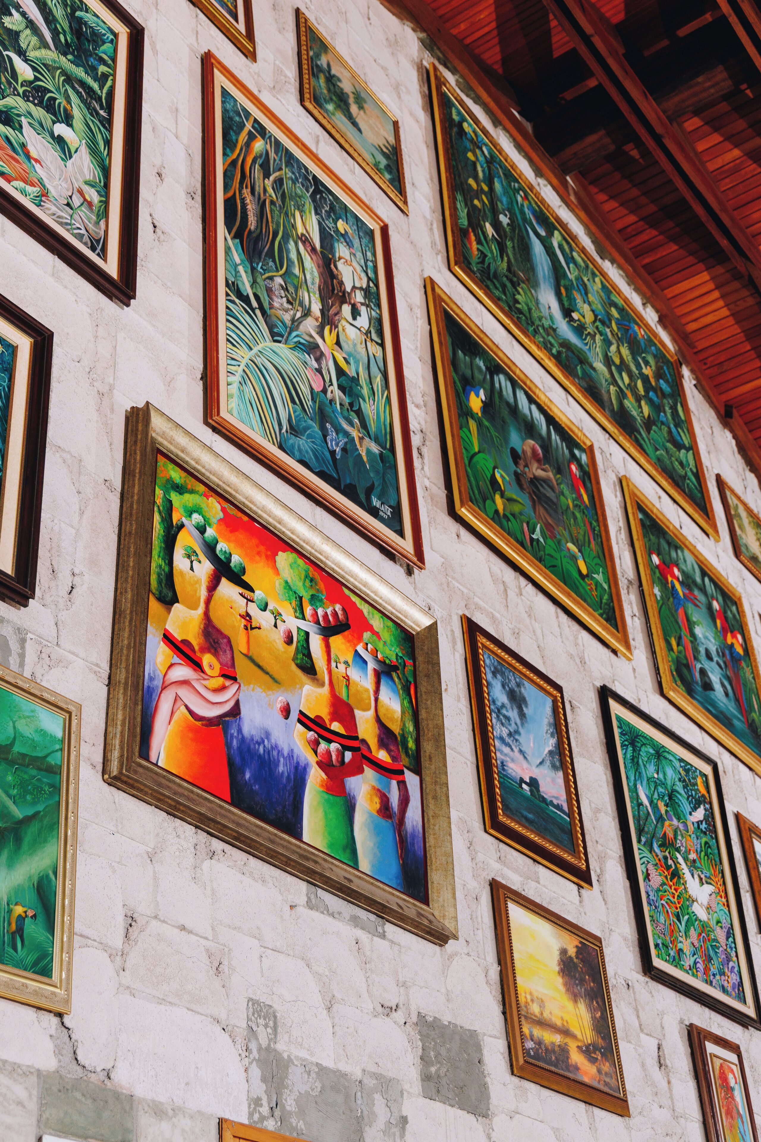 A wall with multiple framed paintings.