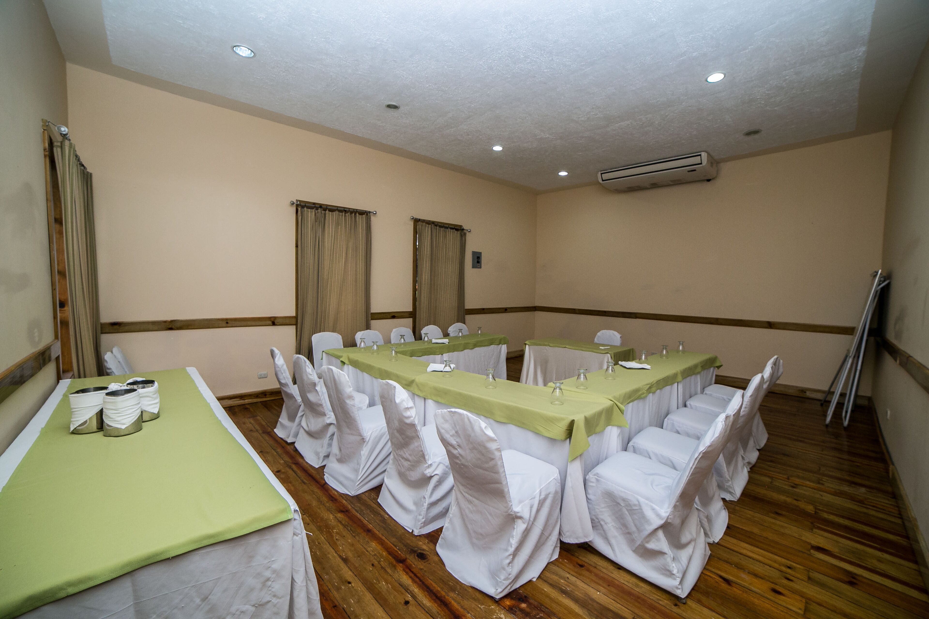 A conference room with long tables, white chairs, and beige walls.