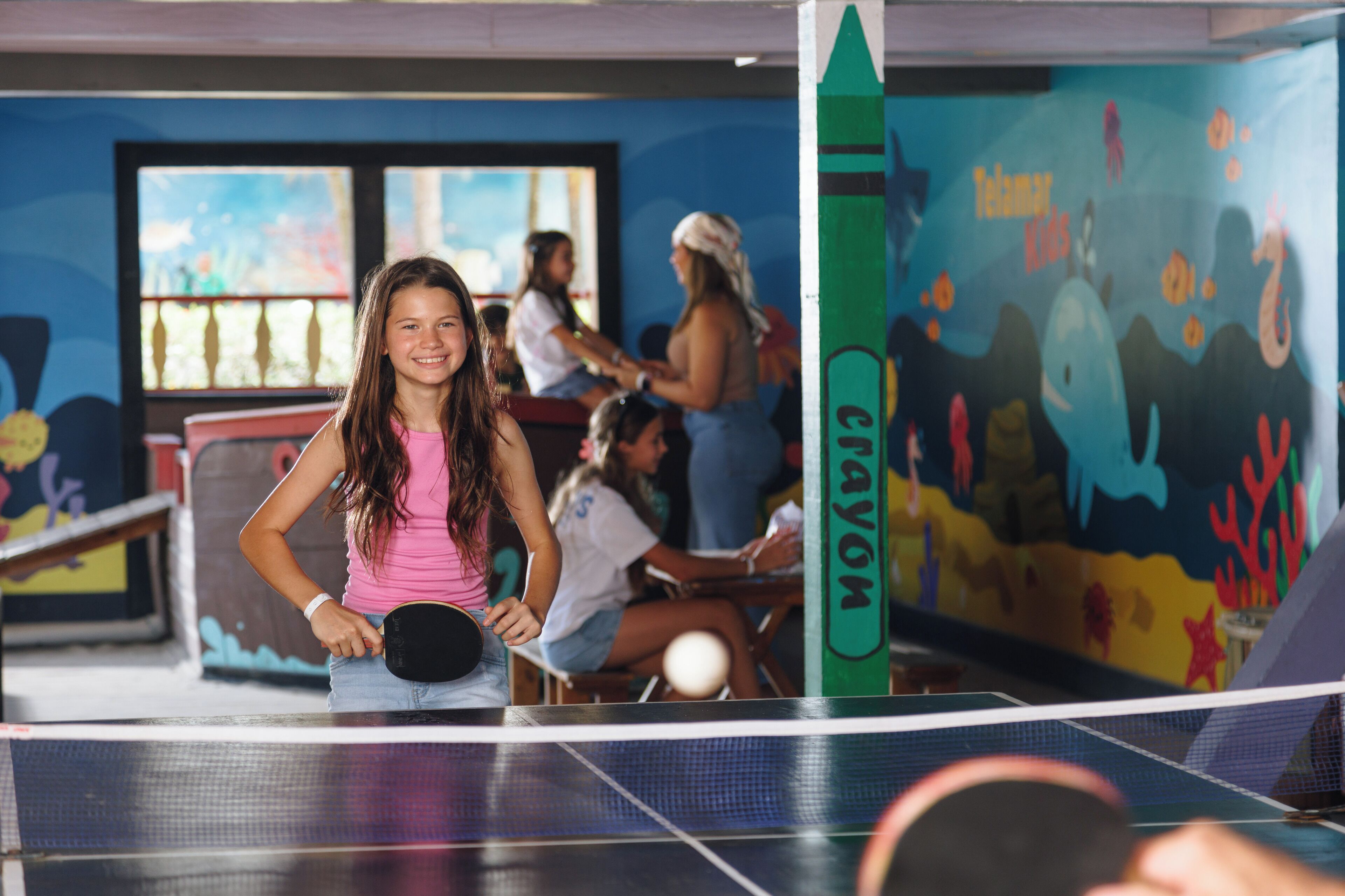 A table tennis table with a net in an indoor recreational area.