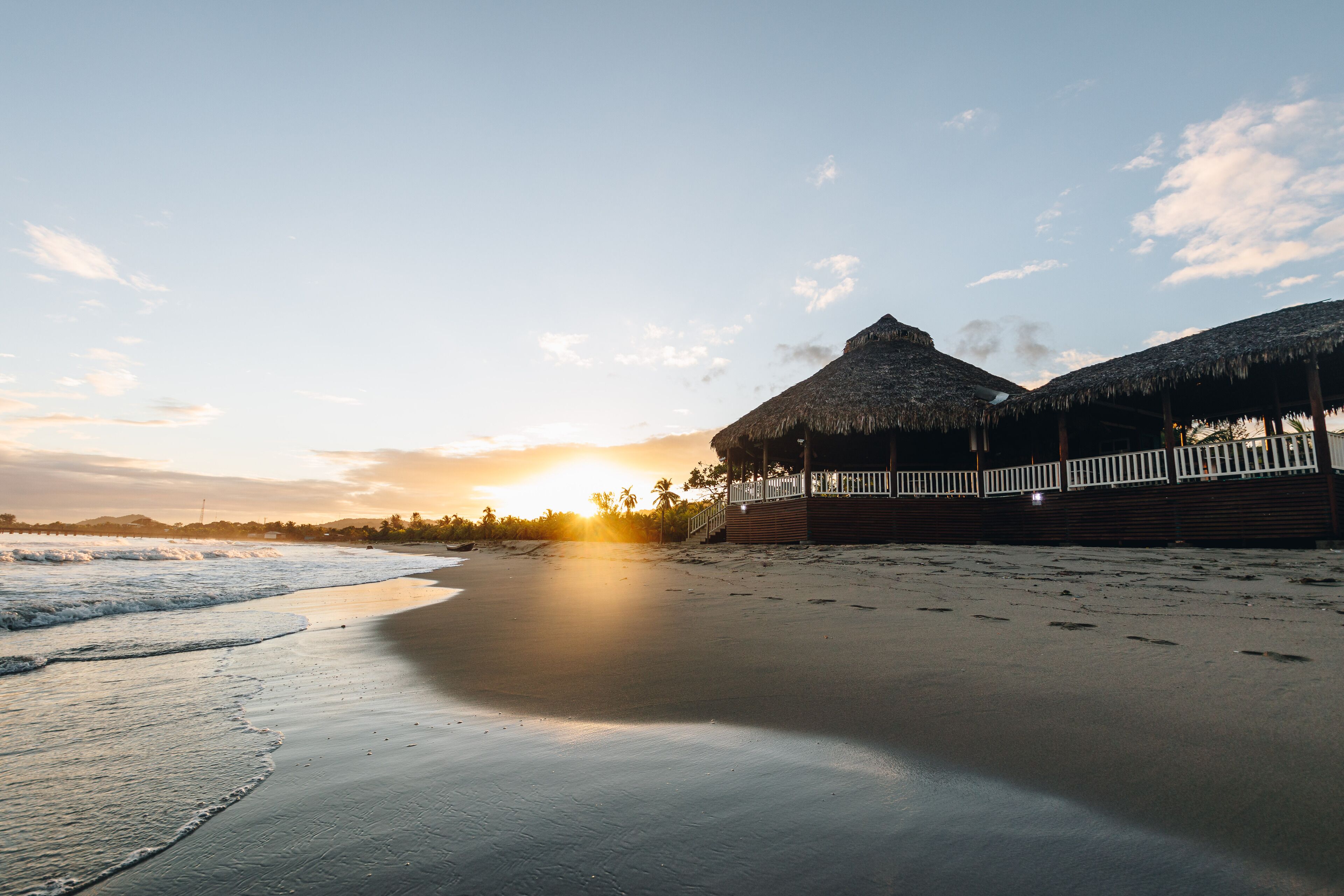 A beach scene with a thatched-roof structure and a wooden deck.