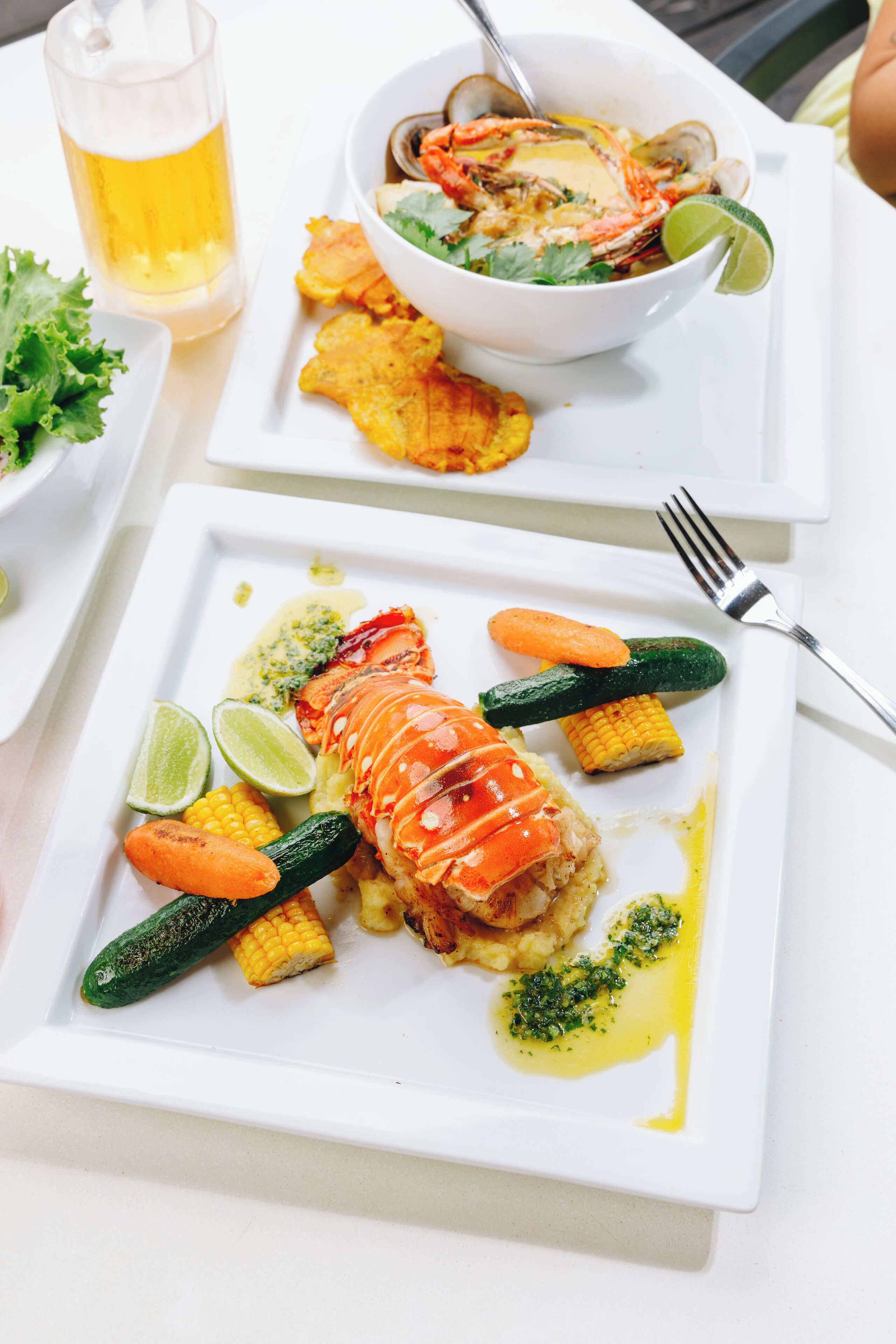 Ein Gericht mit Meeresfrüchten, Hummer, Mais, Karotten und einem Limettenschnitz.