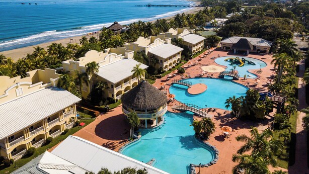 Un resort con varias piscinas, playa y vistas al océano.