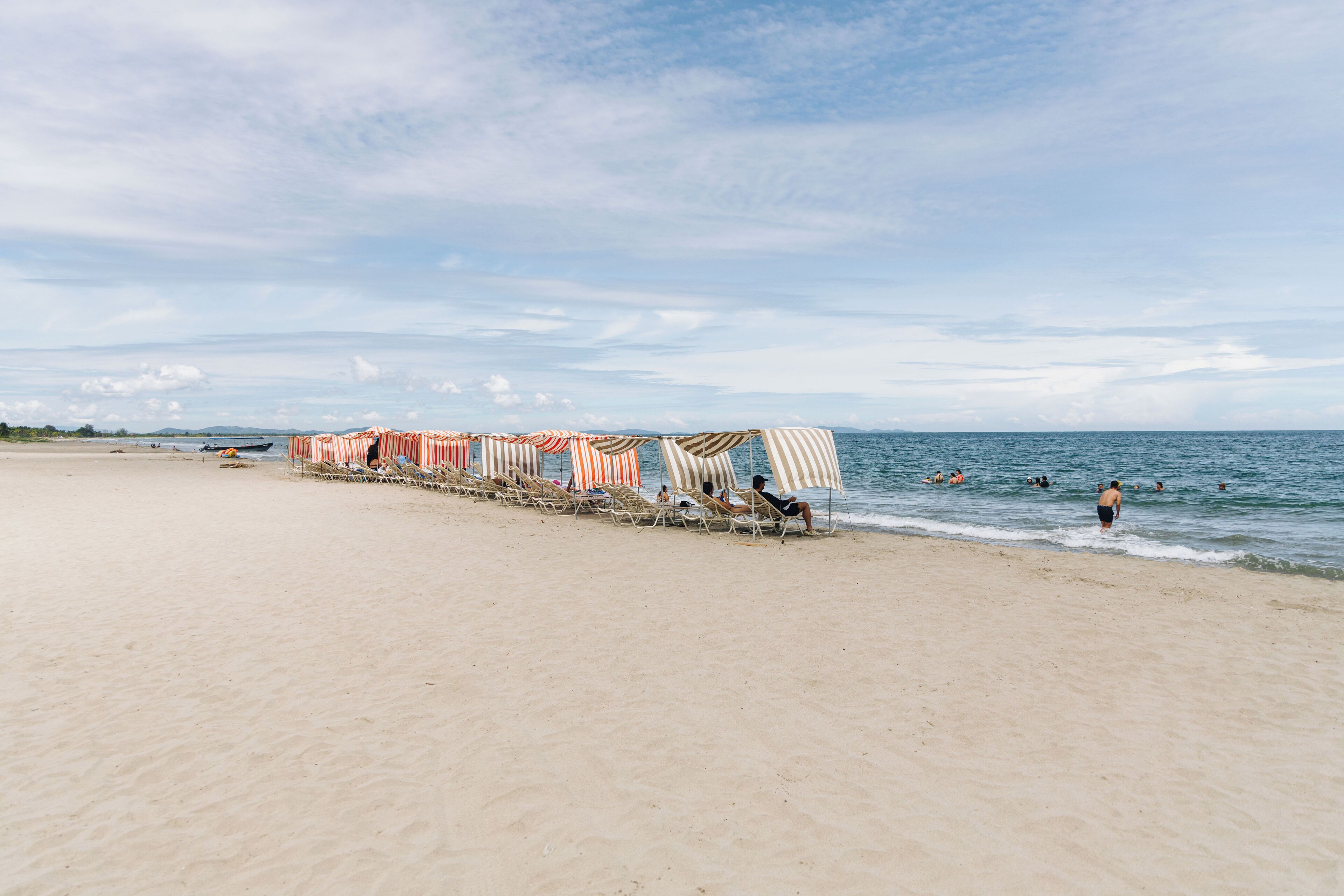 Una playa con hileras de sombrillas a rayas y sillas de playa.