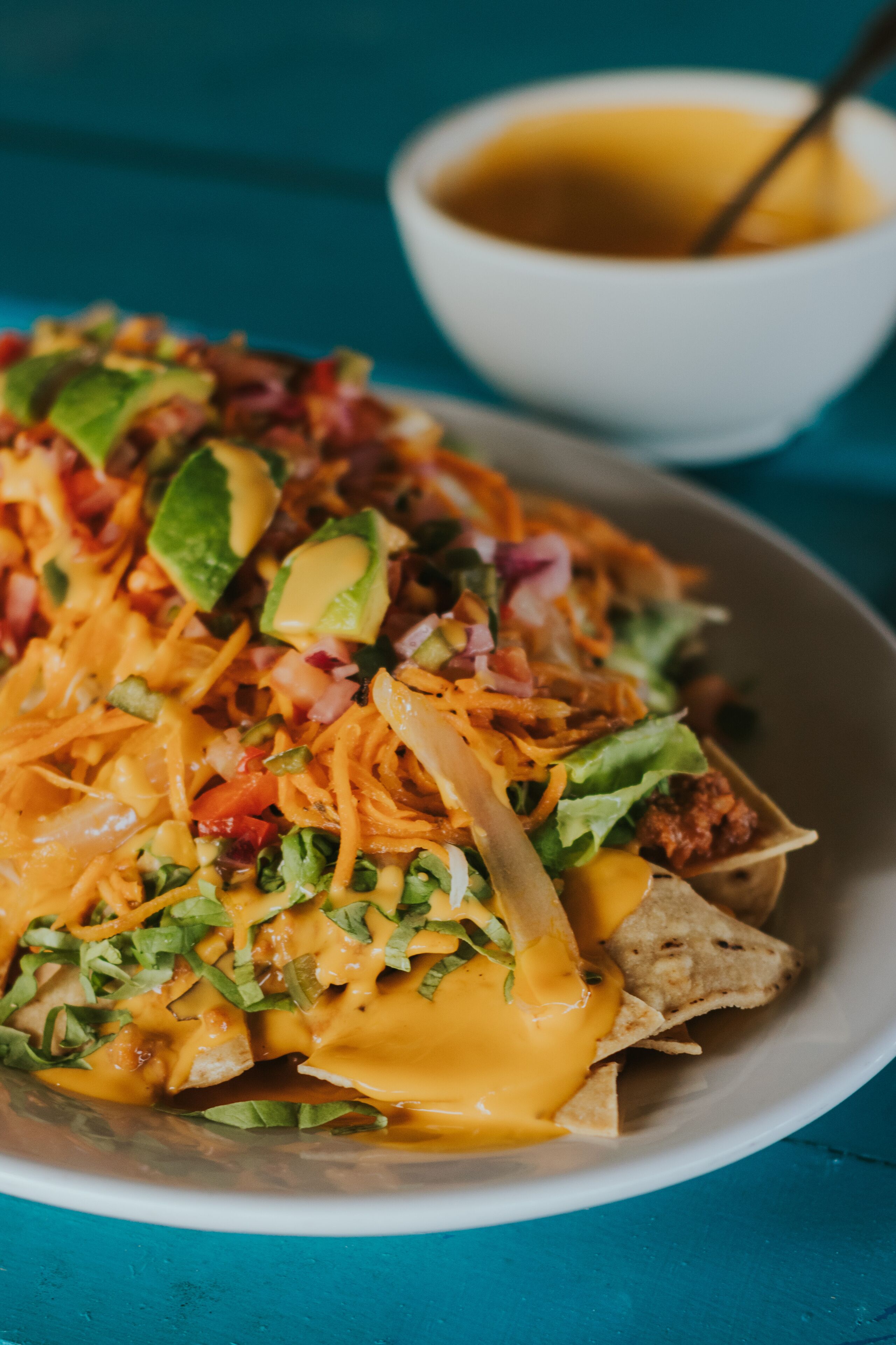 Um prato de nachos coberto com queijo, abacate e outros ingredientes.