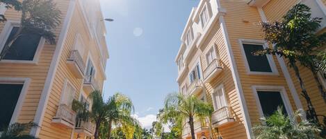 A courtyard with a central fountain, surrounded by palm trees and buildings with balconies.