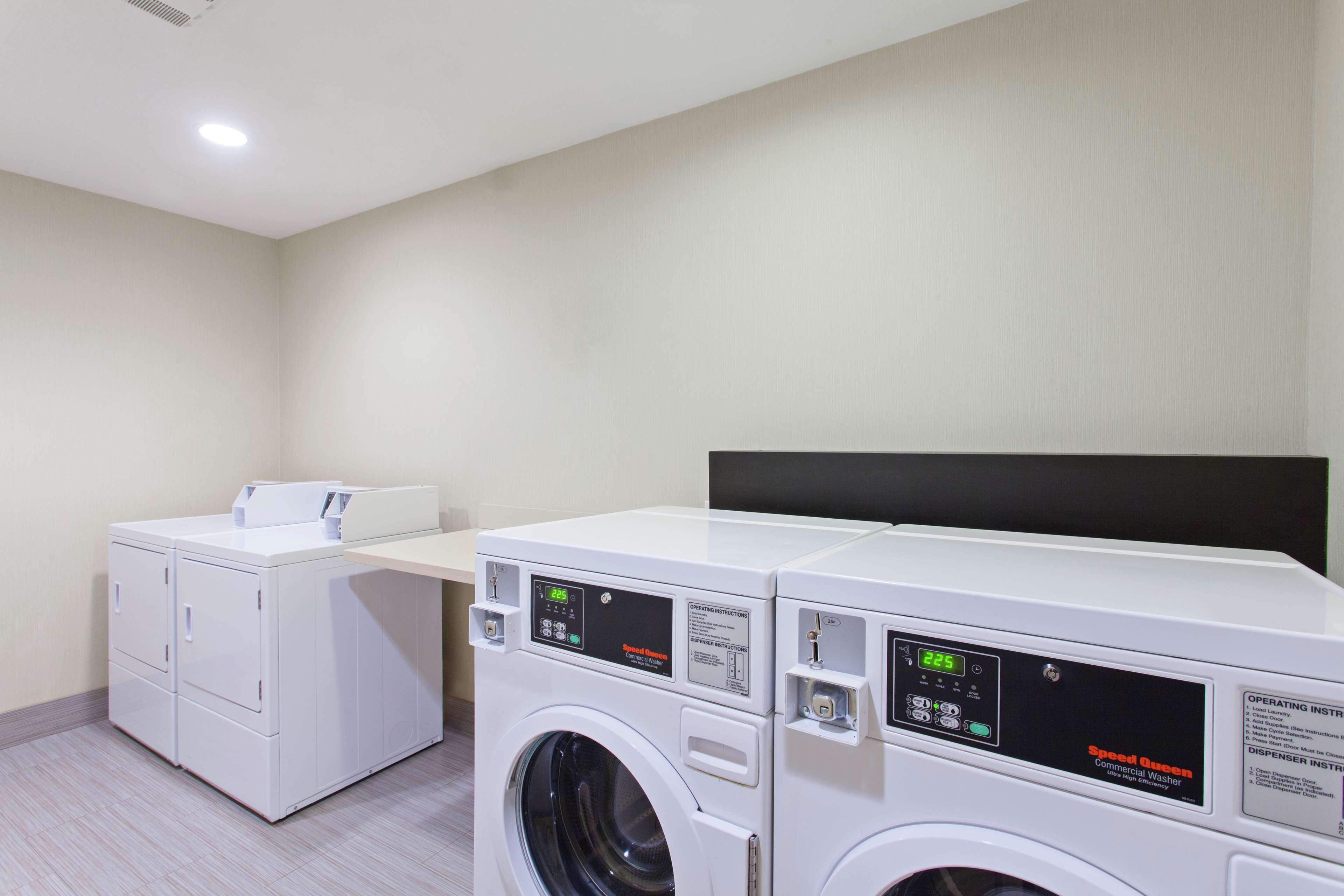 A laundry room with two front-loading washing machines and a dryer.