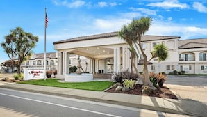 A hotel entrance with a covered patio, palm trees, and a fountain. - Hampton Inn Morgan Hill (Morgan Hill)