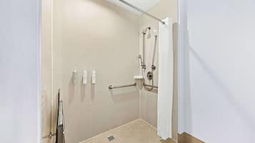 A modern bathroom with a walk-in shower, grab bars, and a hand dryer.