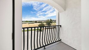 A balcony with a view of a parking lot and distant landscape.