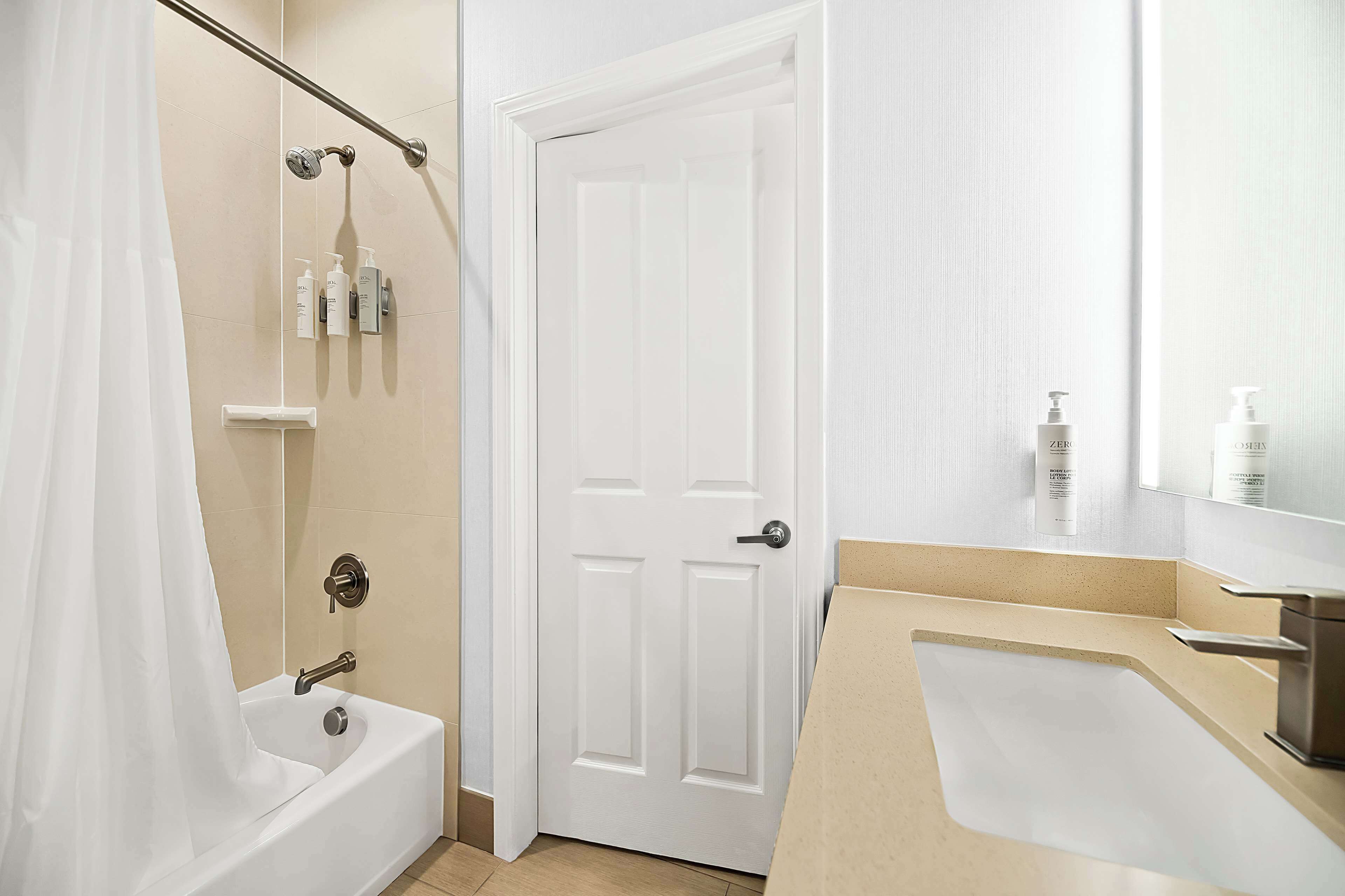 A modern bathroom with a bathtub, shower, and sink.