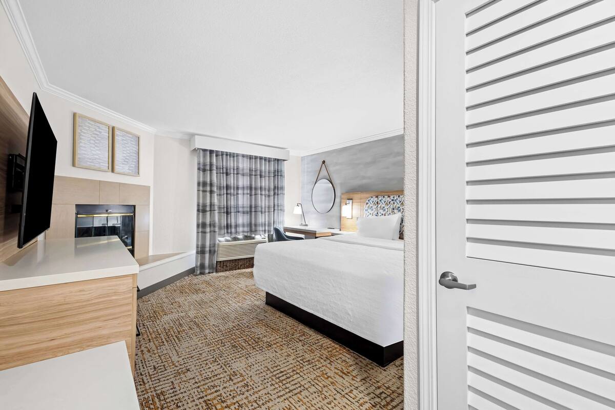A hotel room with a bed, a desk, a TV, and a wardrobe.