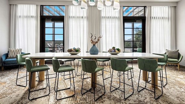 A modern dining area with a large table, green upholstered chairs, and a unique chandelier. - Hampton Inn Morgan Hill (Morgan Hill)