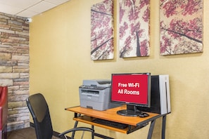 A computer desk with a Brother printer, a HP monitor, and a sign indicating free Wi-Fi in all rooms.