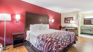Ein Hotelzimmer mit Bett, Nachttischlampen, Schreibtisch und Bad.