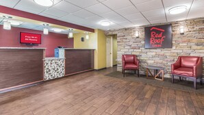 Zona de recepción de un hotel con un letrero de Red Roof Inn, un reloj y un cartel que dice 'Wi-Fi gratis en todas las habitaciones'.