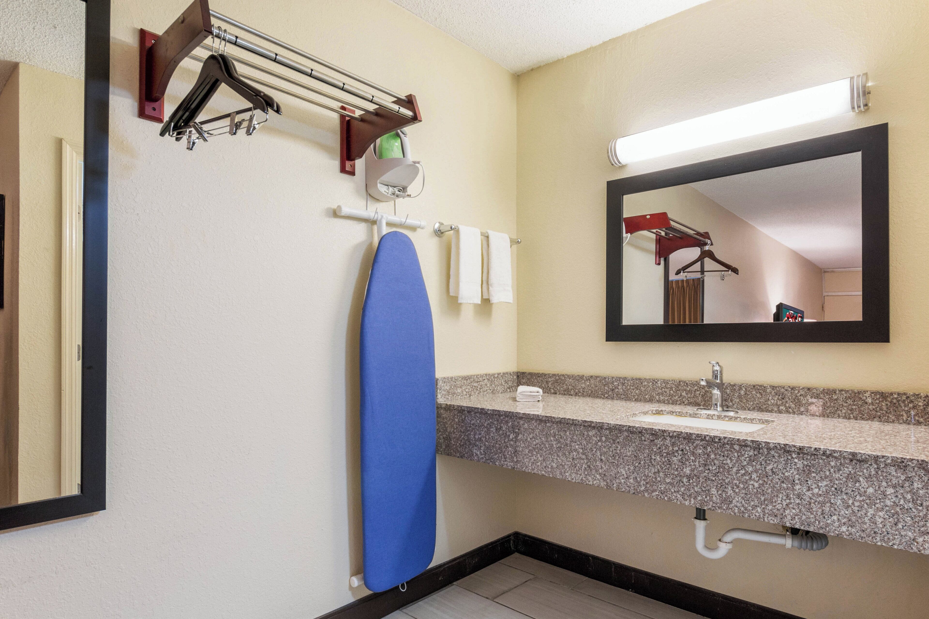 A bathroom with a sink, mirror, towel rack, and a blue towel.