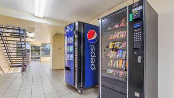 Ein Verkaufsautomatenbereich mit Pepsi- und Fushion-Automaten, eine Metalltreppe und Blick nach draußen.