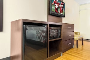 Una habitación con un armario de madera, un televisor montado encima y una silla.