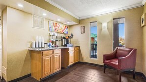 Habitación de hotel con kitchenette, una butaca de cuero rojo y una ventana con vistas al exterior.