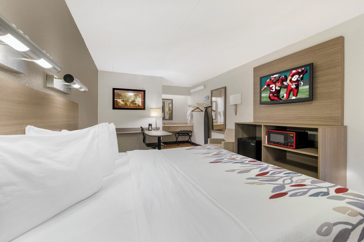 Une chambre d’hôtel équipée d’un lit, d’un bureau, d’une chaise, d’une télévision et d’un four à micro-ondes.