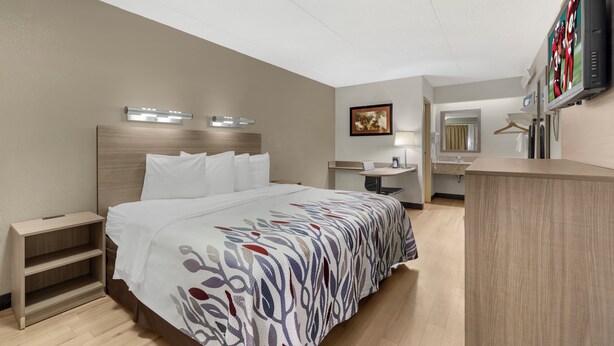 Une chambre d’hôtel comprenant un lit, des tables de chevet, un bureau, un miroir et un téléviseur.