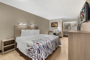 A hotel room with a bed, bedside tables, a desk, a mirror, and a television. - Red Roof Inn Buffalo - Niagara Airport (Bowmansville)