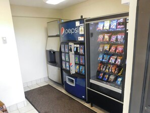 Un espace comprenant un distributeur automatique et un réfrigérateur à boissons de la marque Pepsi, ainsi qu’un autre distributeur automatique de collations.