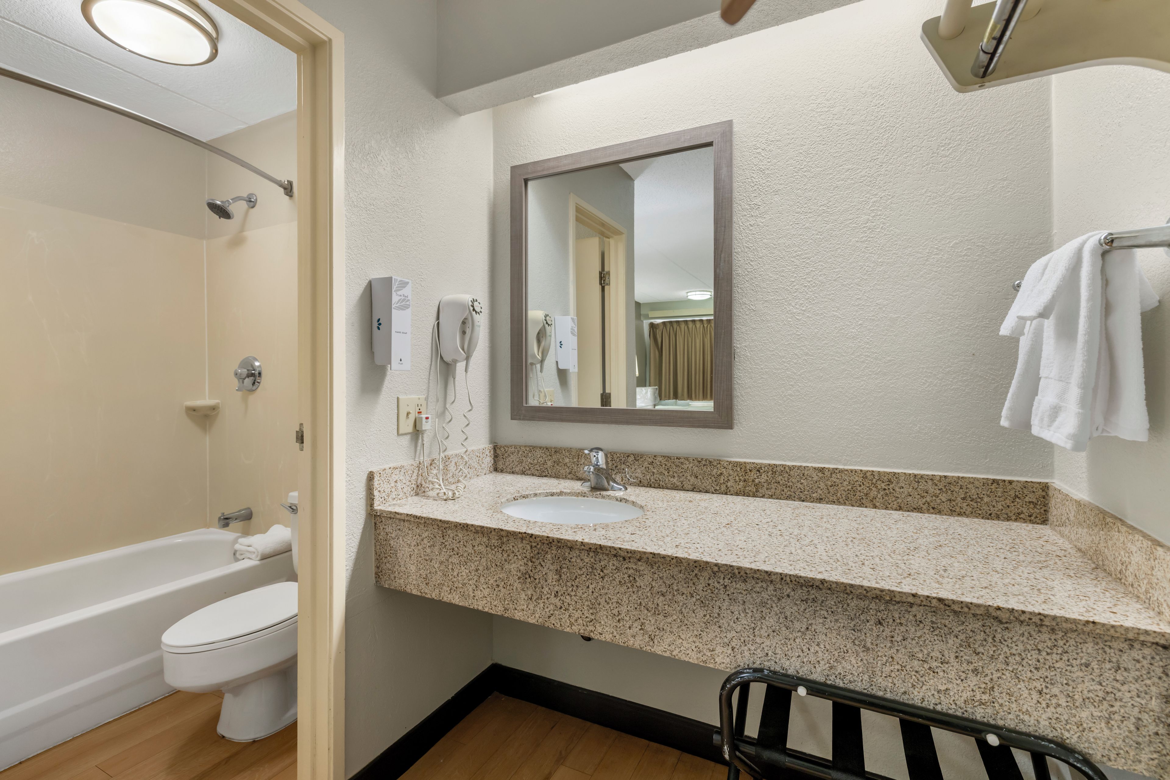 Une salle de bain équipée d’un lavabo, d’un miroir, d’un porte-serviettes et d’un espace douche.